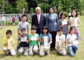 樹名板を手にする児童に囲まれて 井上村長さんと清原市長